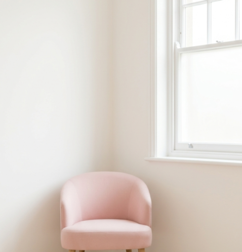A pale pink armchair beside a sash window